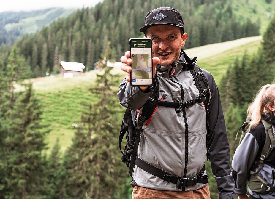 komoot bei Wanderung_Rene-komoot Mann zeigt Handy bei Wanderung in Kamera